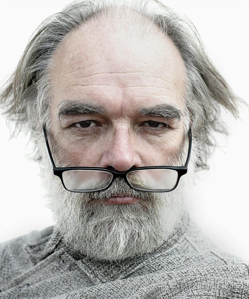 Detailed close-up portrait of an elderly man with glasses and a thoughtful expression.
